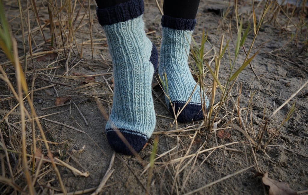 pair of feet in blue socks standing in the reed