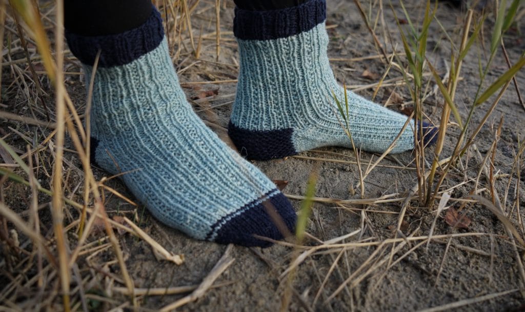 pair of feet in blue socks standing in the reed