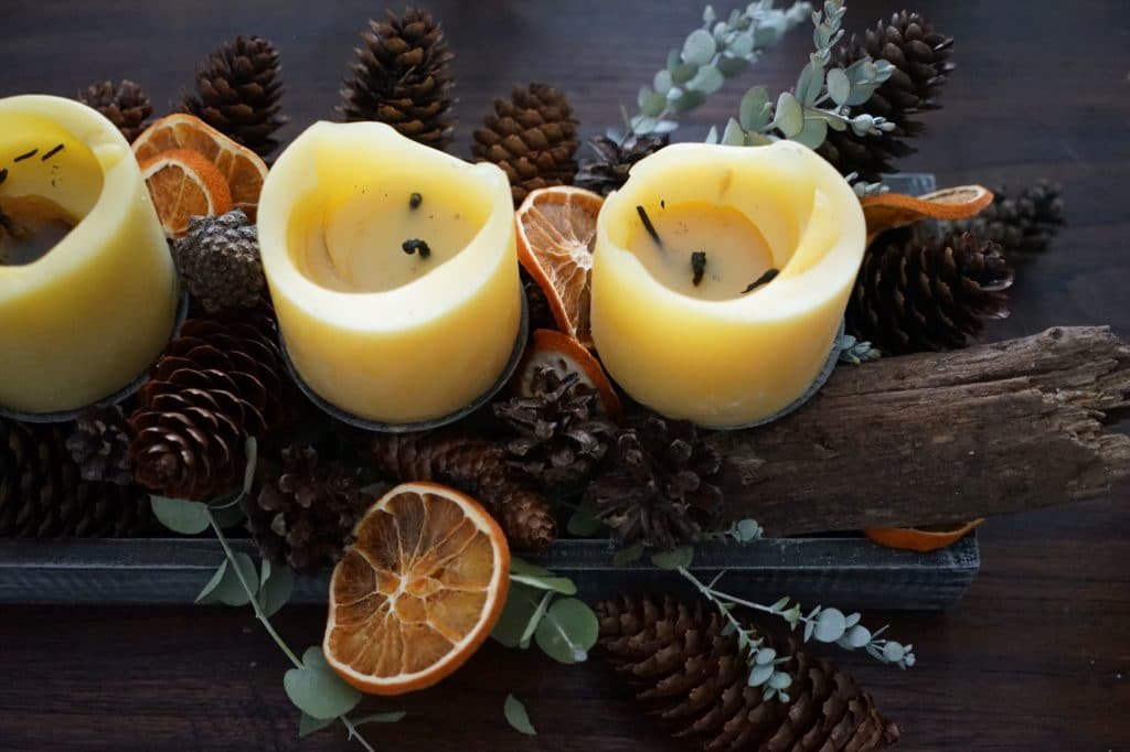 part of an advent wreath with half burned beeswax candles, eucalyptus branches, dried orange slices and pinecones