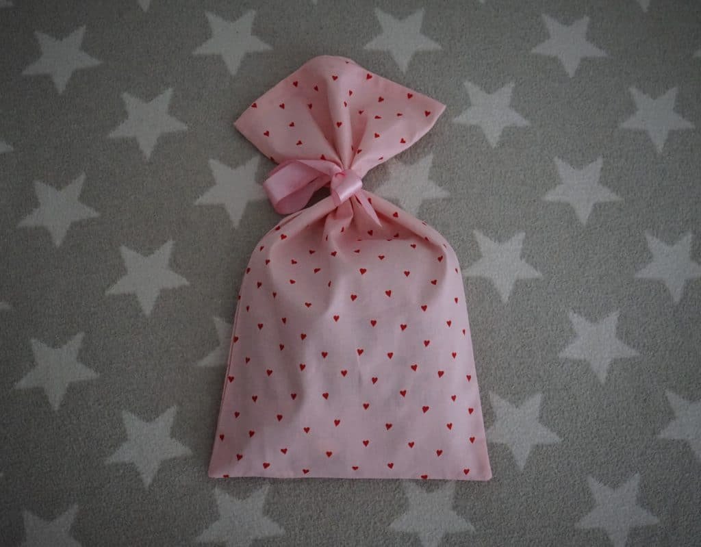 pink fabric bag with red hearts and a pink bow on a grey and white star background