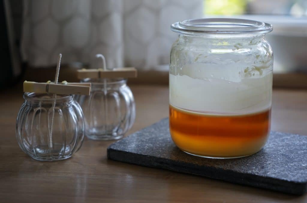 melted beeswax slightly cooled and two glass jars with wicks