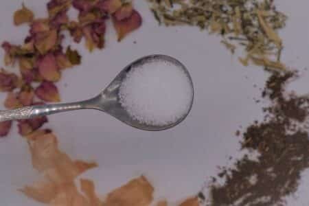 a spoon with alum above several natural dye materials (onion skins, madder, fustic, rose petals), mordants for natural dyes