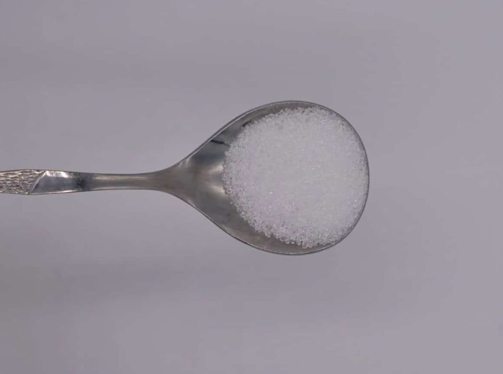 a hand holding a spoon with alum