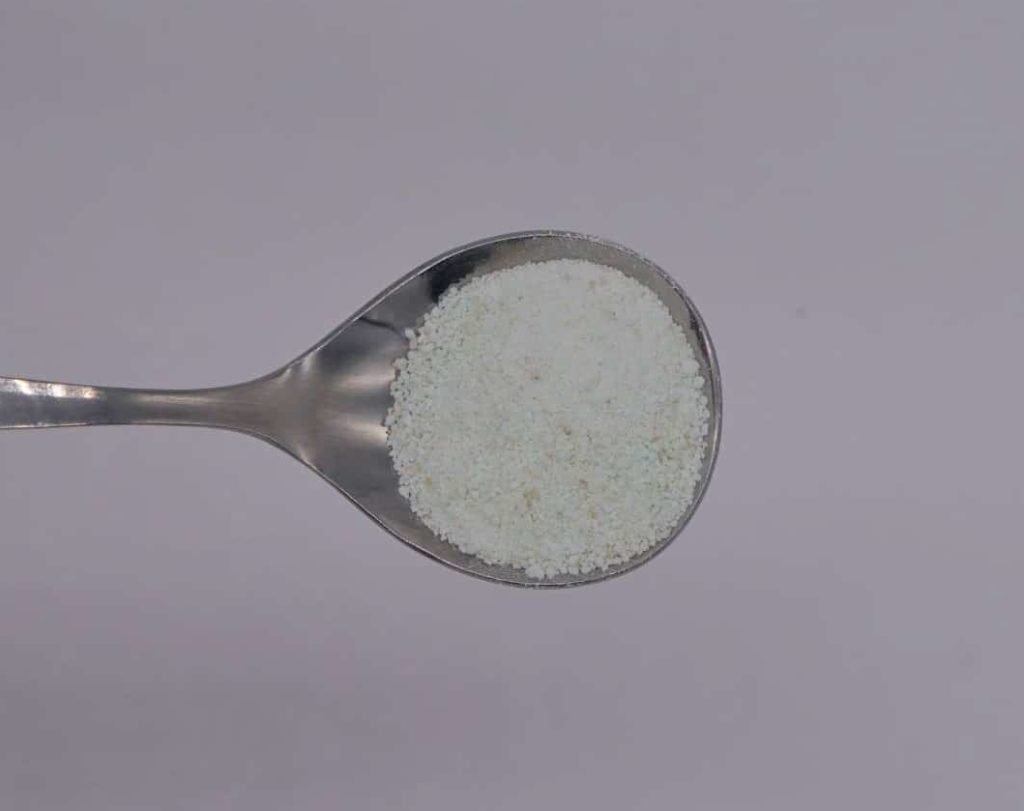 a hand holding a spoon with iron (II) sulfate for natural dyeing