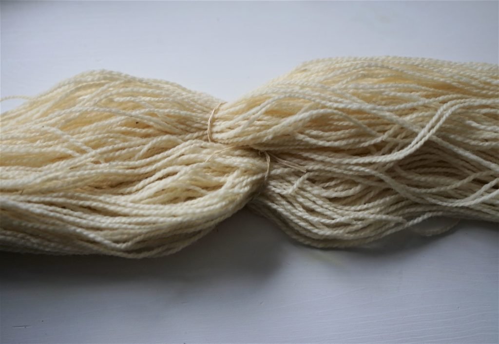 undyed hank of yarn with a tie around it