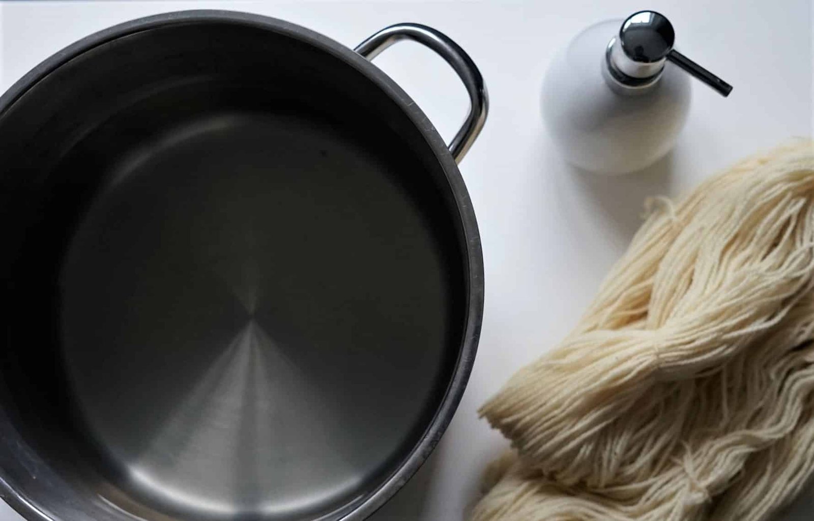 pot with water, soap dispenser and an undyed hank of yarn