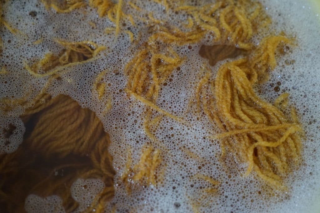 yellow skein of yarn in soapy water
