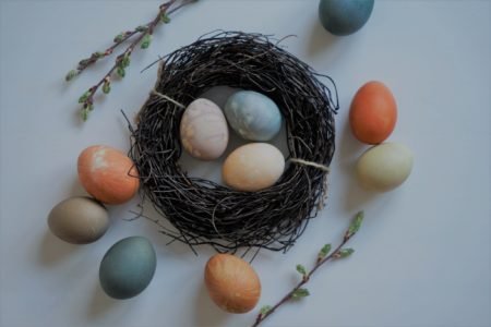 several naturally dyed easter eggs and a wooden nest