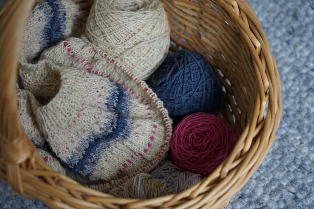 knitting work in progress in a basket and some balls of yarn (test knit for alicia plummer)