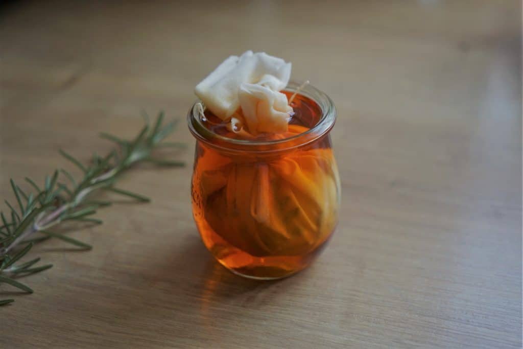 an egg wrapped in a piece of fabric in a small jar with an orange dye solution (how to dye easter eggs with natural dyes)