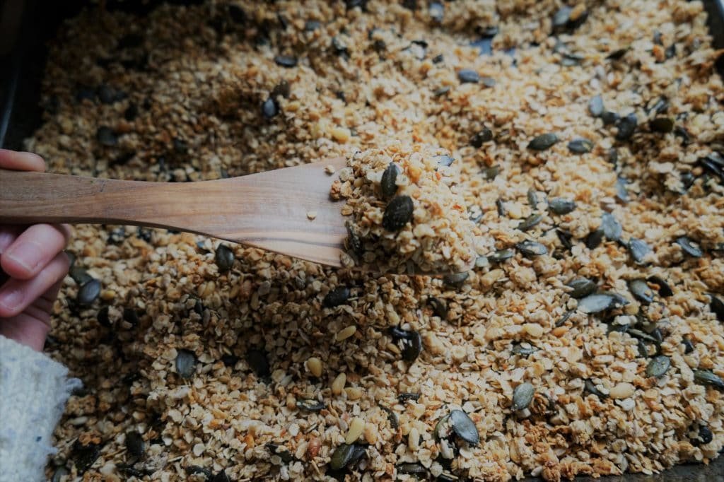 homemade granola and a hand holding a wooden spoon