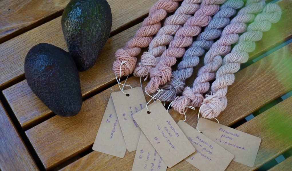 six mini skeins of yarns with tags and two avocados