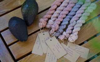 six mini skeins of yarns with tags and two avocados