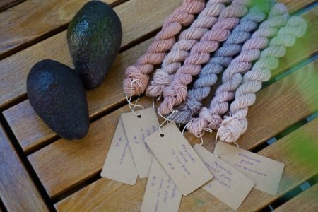 six mini skeins of yarns with tags and two avocados