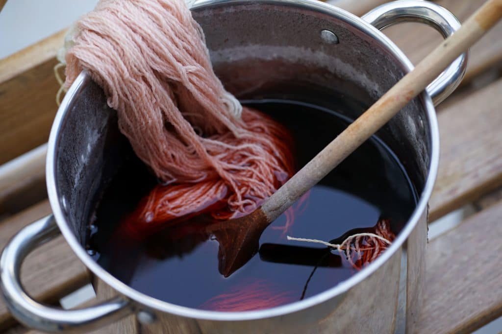 skein of yarn in a dye pot and a wooden spoon