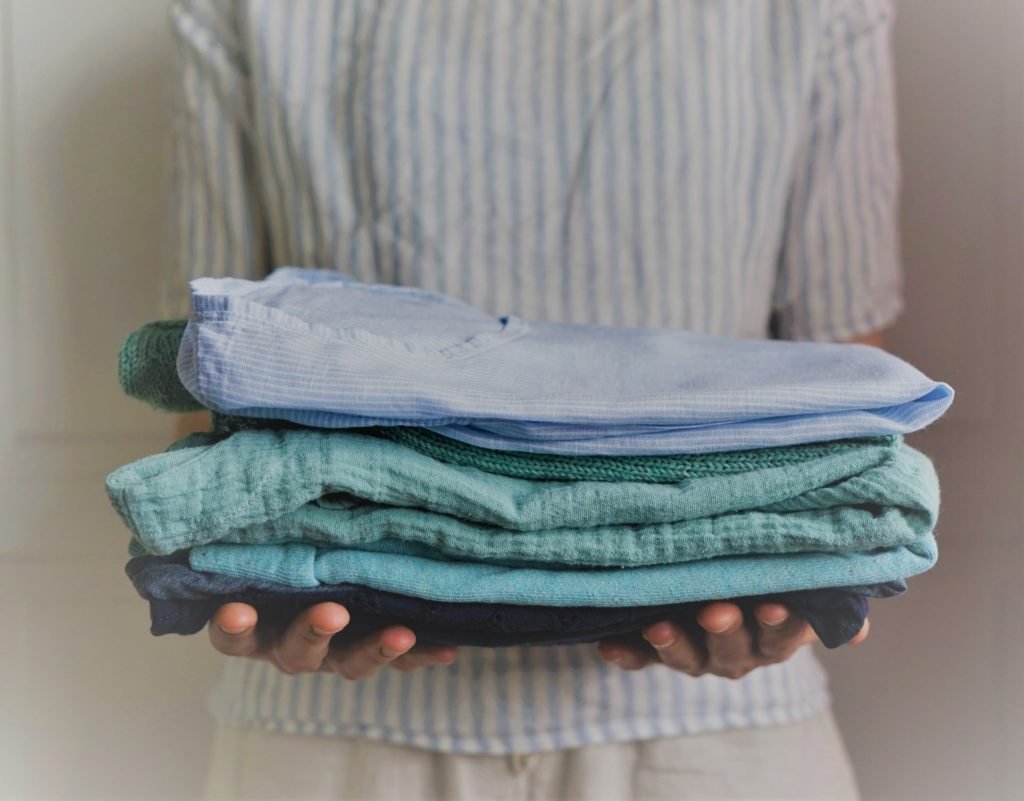 woman holding a stack of handmade clothes