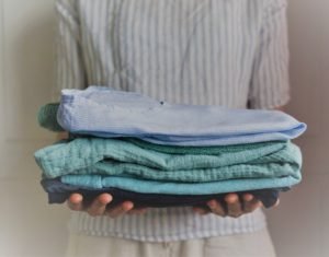 woman holding a stack of handmade clothes