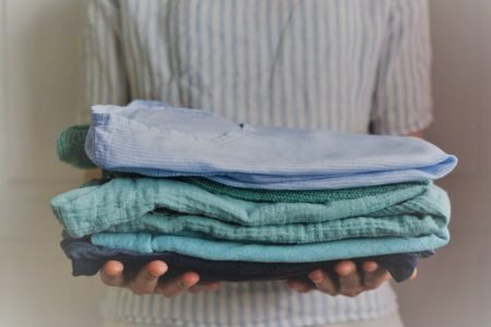 woman holding a stack of handmade clothes