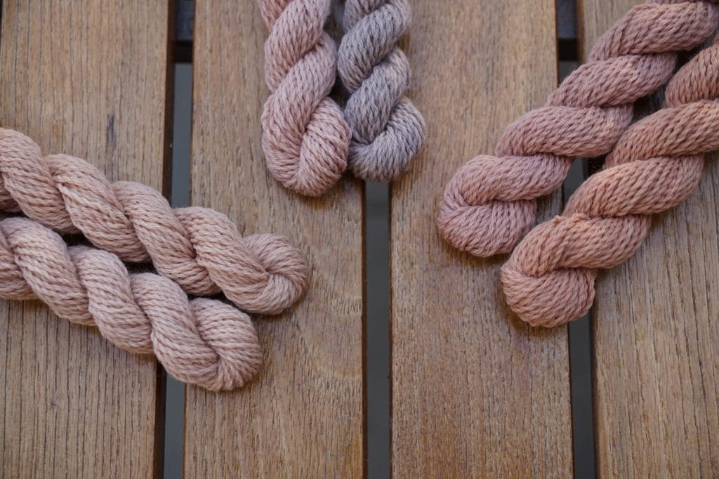 six mini skeins of yarn in different shades of peach, apricot, mauve and dusty pink