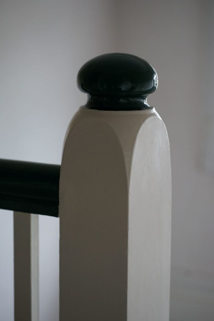 wooden stair rail covered in green and white paint