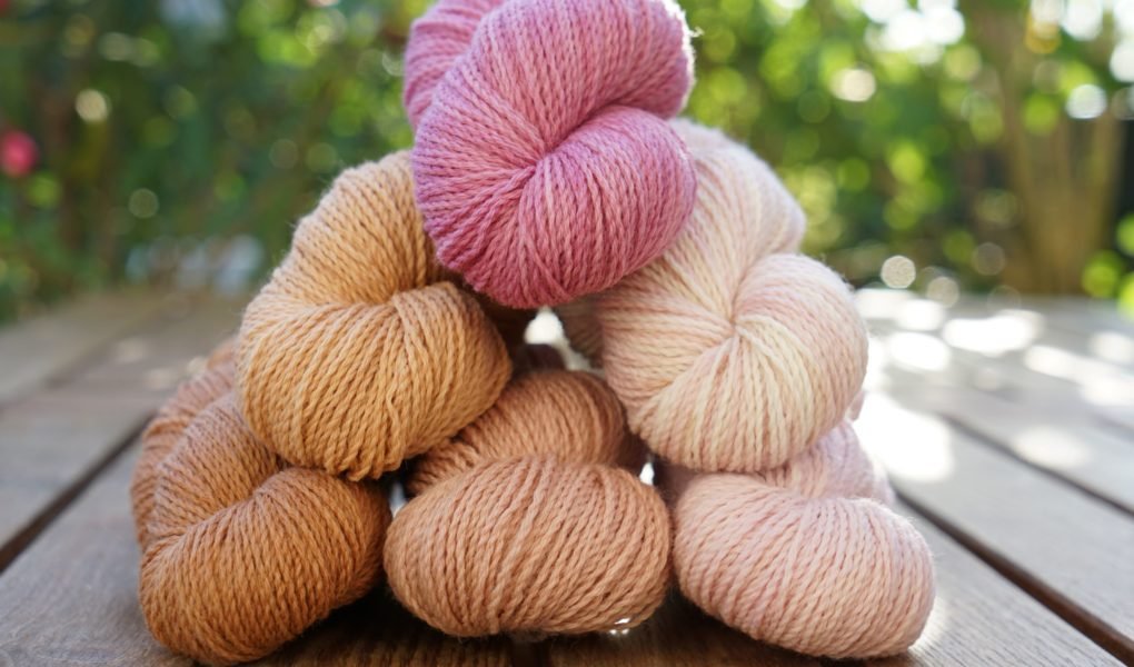 six mini skeins of yarn in different shades of peach, apricot, mauve and dusty pink