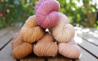 six mini skeins of yarn in different shades of peach, apricot, mauve and dusty pink