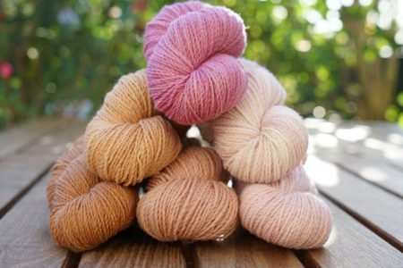 six mini skeins of yarn in different shades of peach, apricot, mauve and dusty pink