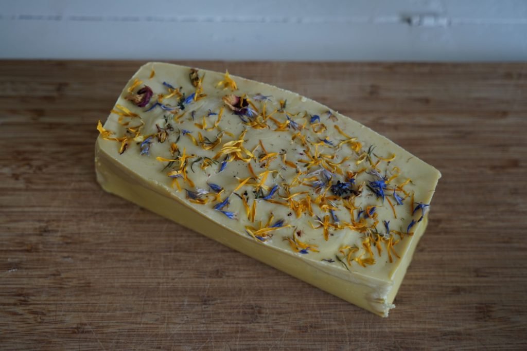 loaf of soap, yellow with dried wildflowers on top