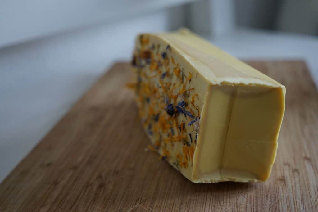 loaf of yellow soap on the side on a cutting board