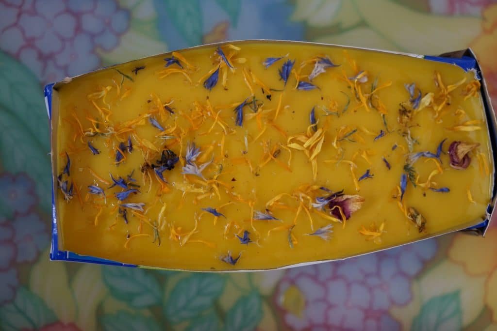 bright yellow loaf of soap in a milk box topped with dried flowers