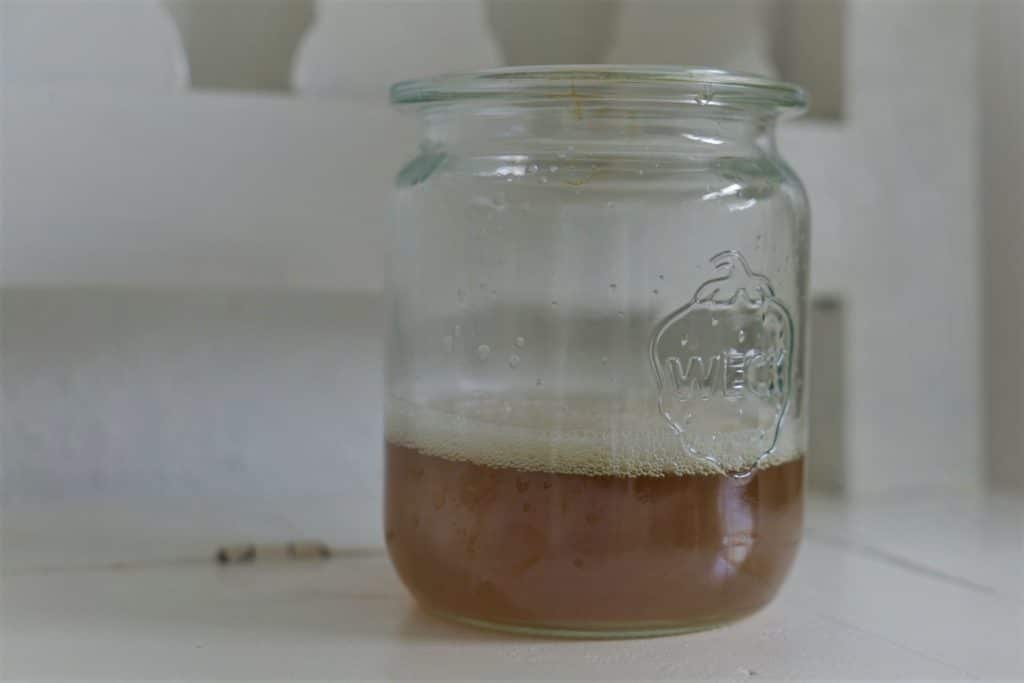 goldenrod dye solution in a glass yarn on a white wooden bench