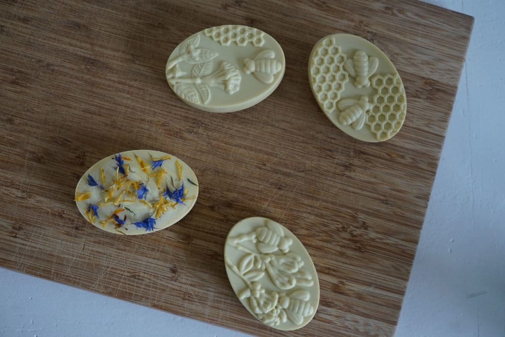 four pieces of handmade yellow cold process soap on a wooden cutting board