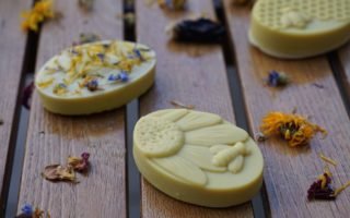 three pieces of goldenrod honey soap with bees, topped with dried flowers