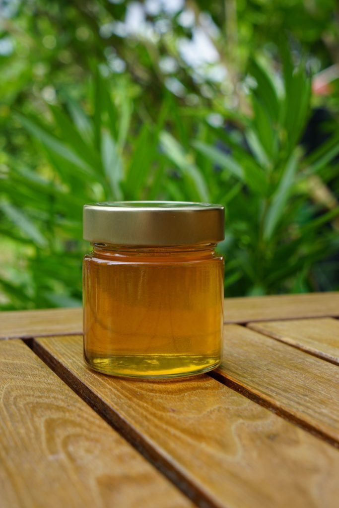 glass of golden honey on a wooden table