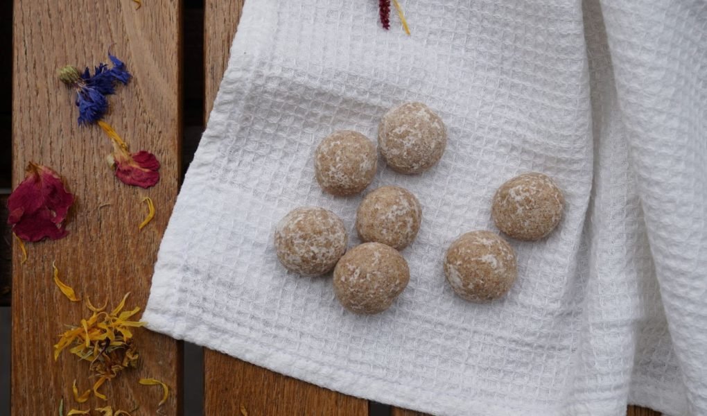 diy aroma stones on a white kitchen towel on a wooden table next to some colourful dried flowers