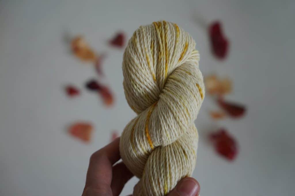 white skein of yarn with yellow and green speckles dyed with onion skins