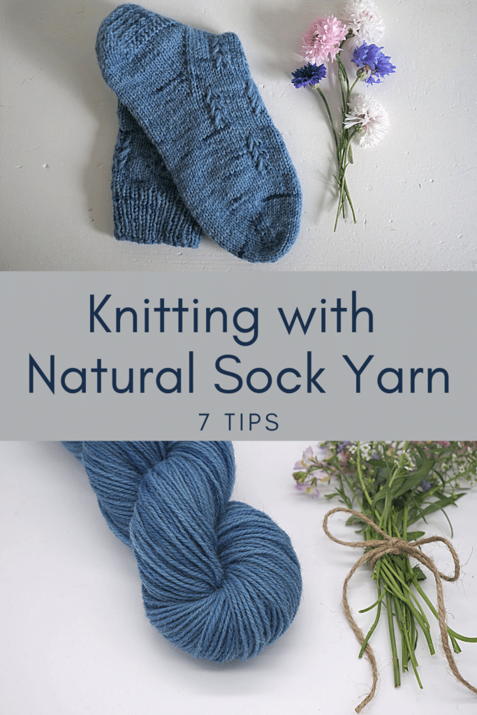 a handknitted blue sock, a blue skein of yarn and some flowers on a white background