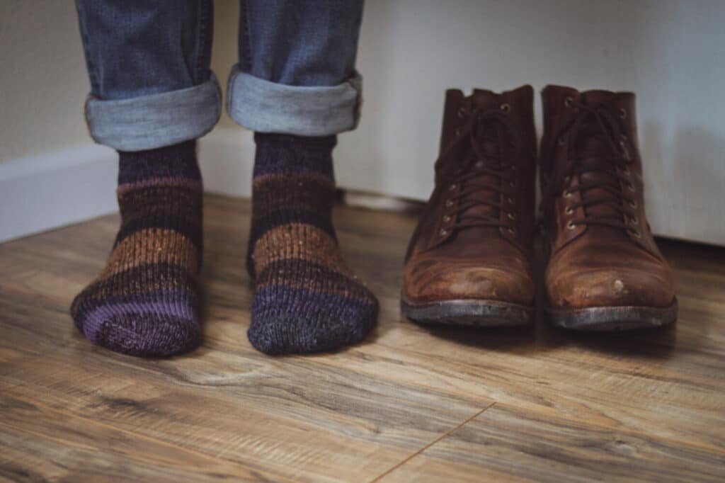 a scrappy pair of socks worn by somebody next to a pair of brown shoes