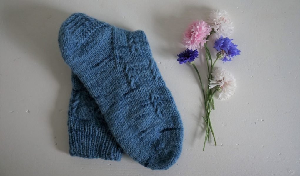 a blue hand knitted song a some flowers next to it