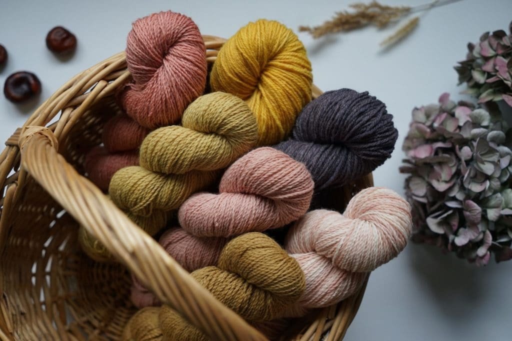 a wooden basket full of fall coloured sock yarn from rosemary & pines fiber arts