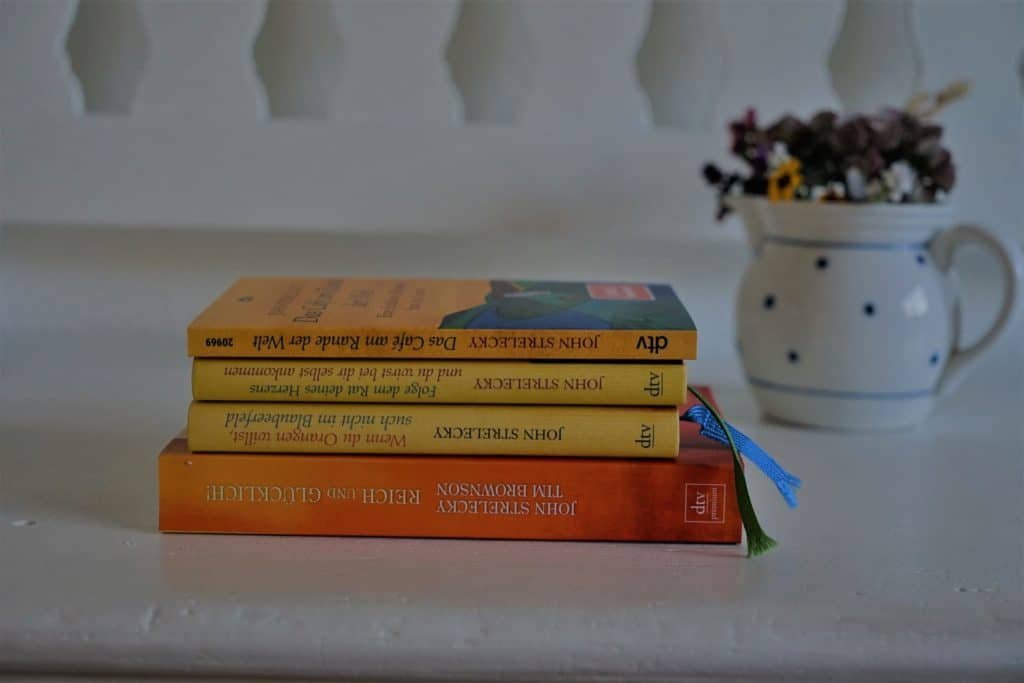 a stack of four books by John Strelecky