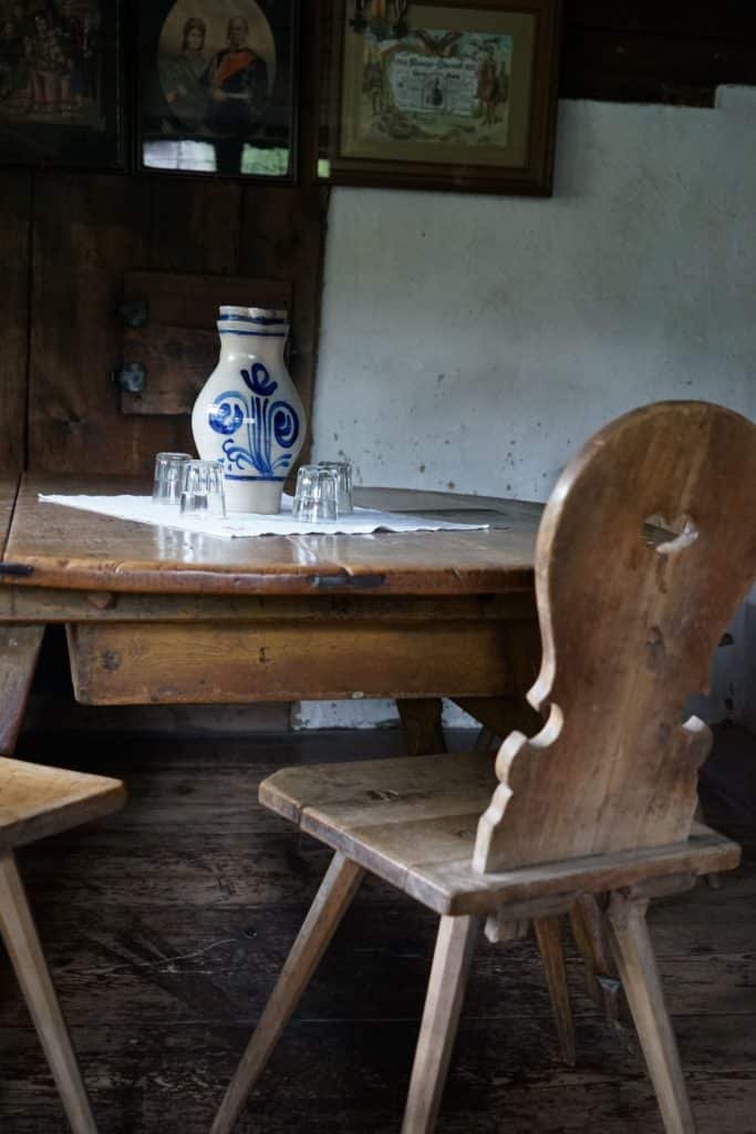 a wooden stool and a white and blue ceramic jug on a wooden table
