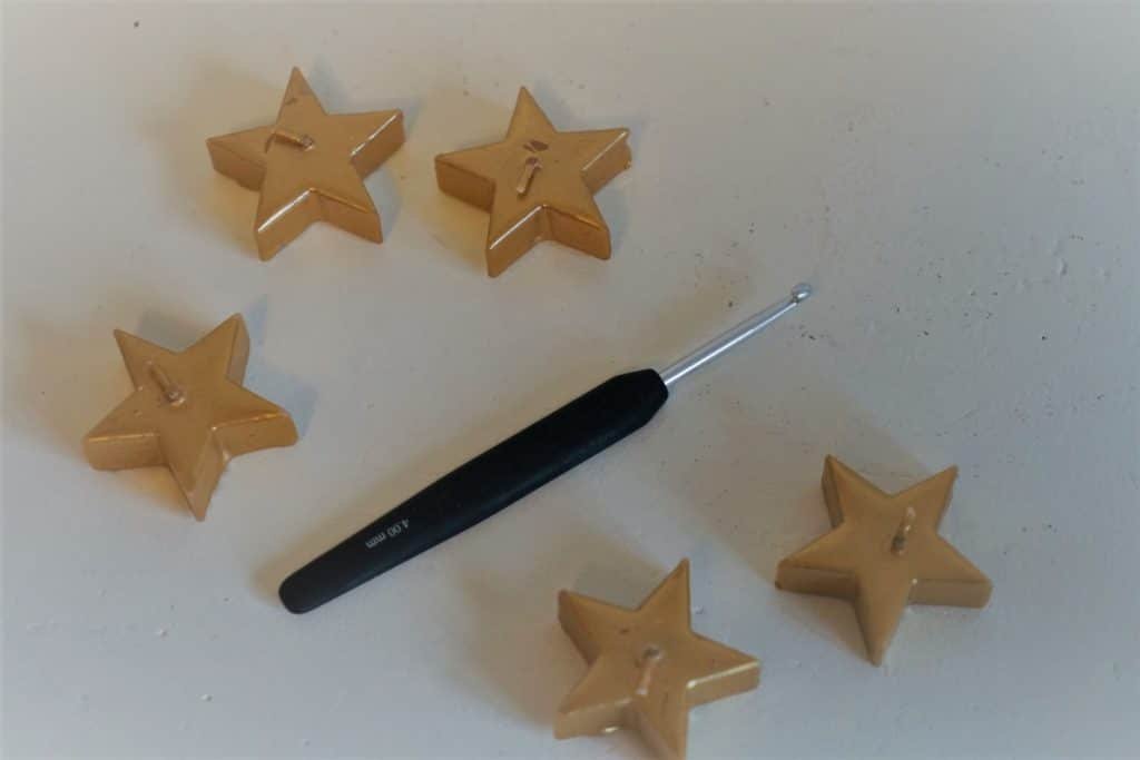 crochet hook and some golden star candles