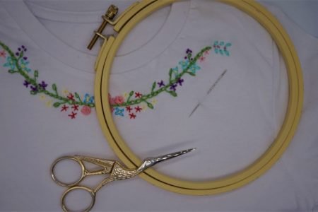 floral garland embroidery on a white t-shirt along with an embroidery hoop and scissors