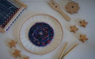 weaving loom, knitting fork, knitting needle and a knotting star along with some golden star shaped candles