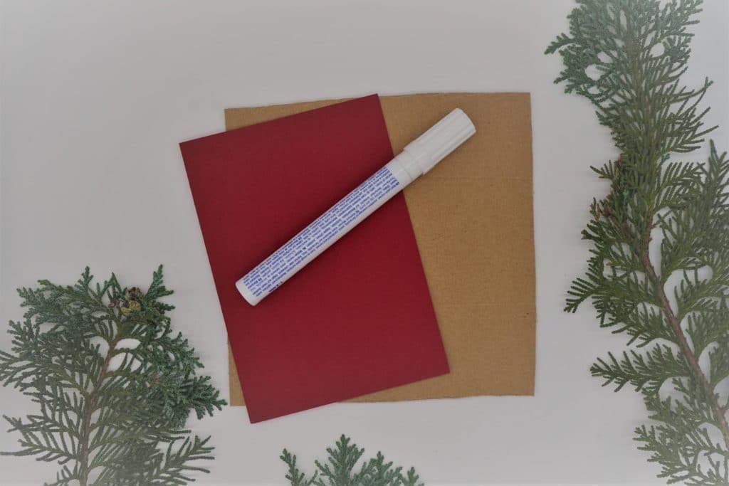 a red blank card, a piece of cardboard and a white permanent marker