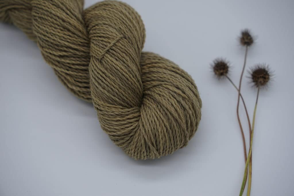 a greyish green colored skein of yarn naturally dyed with rosemary