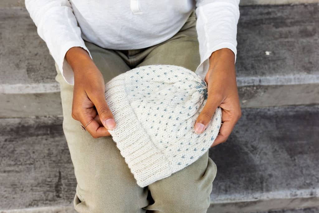 two hands holding a handknitted hat