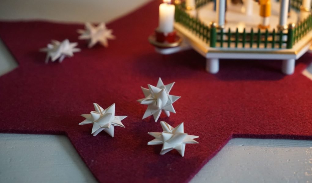 a handful of paper froebel stars and a wooden pyramid in the background