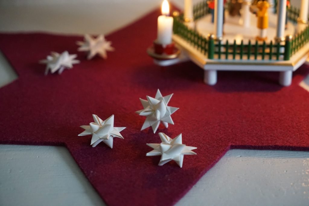 a handful of paper froebel stars and a wooden pyramid in the background